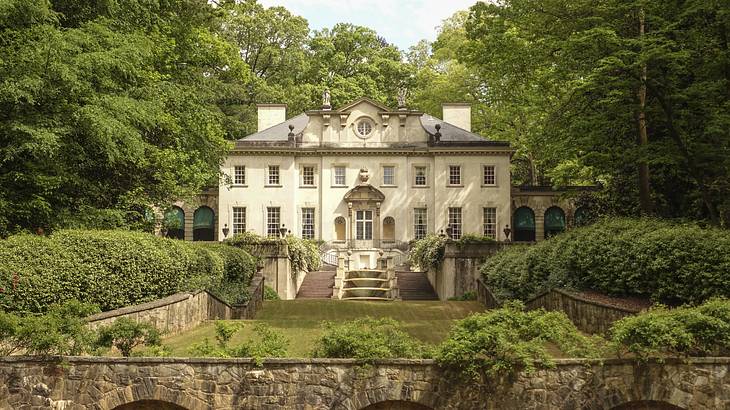 A large renaissance-inspired white house with a patio garden in front of it