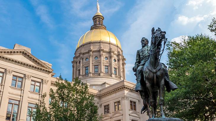 A statue of a man riding a horse next to a dome-like building on a sunny day