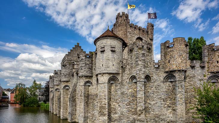 A giant medieval castle made of stone under a blue sky with some clouds