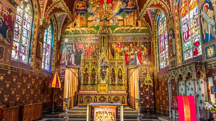 A church interior filled with paintings and stained glass windows of religious scenes