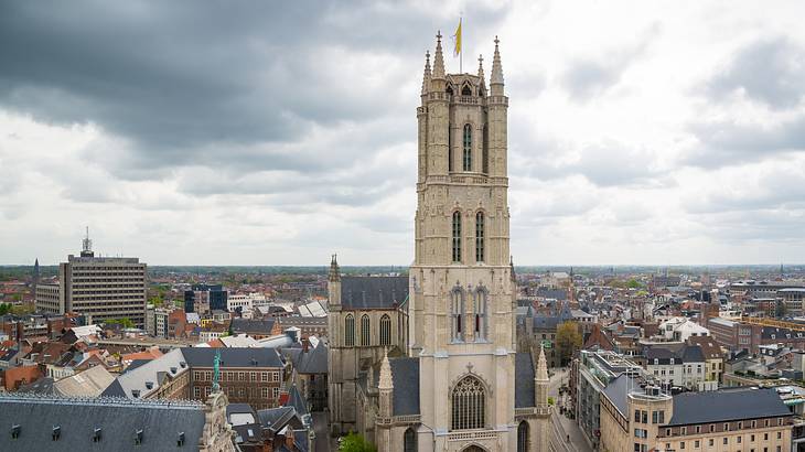 A tall church building in the middle of a city under a cloudy sky