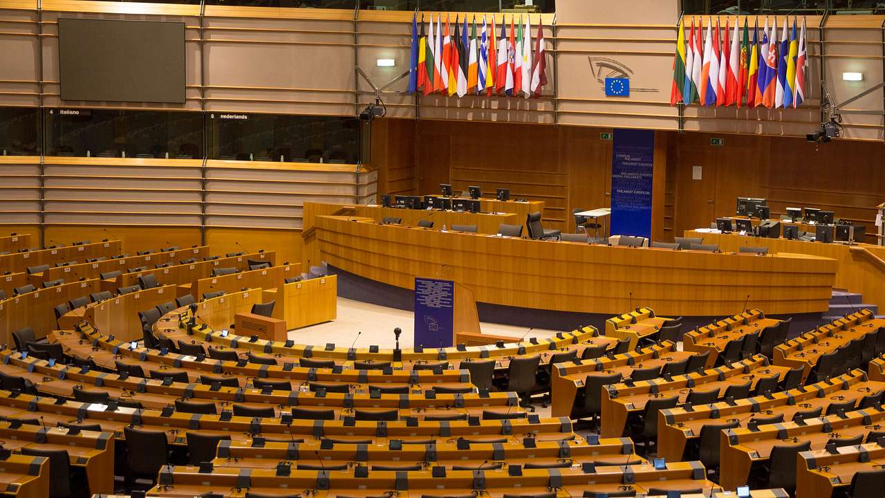 A semicircular plenary chamber with a platform in the middle and European flags