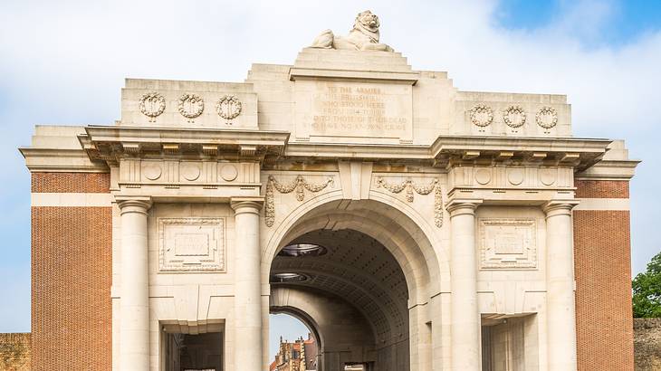 A tall, stone archway with a lion atop it over an empty road