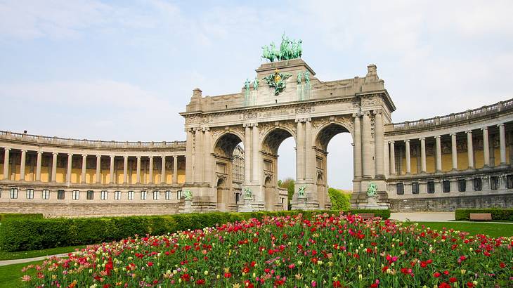 Three side-by-side tall archways and a garden of red flowers in front