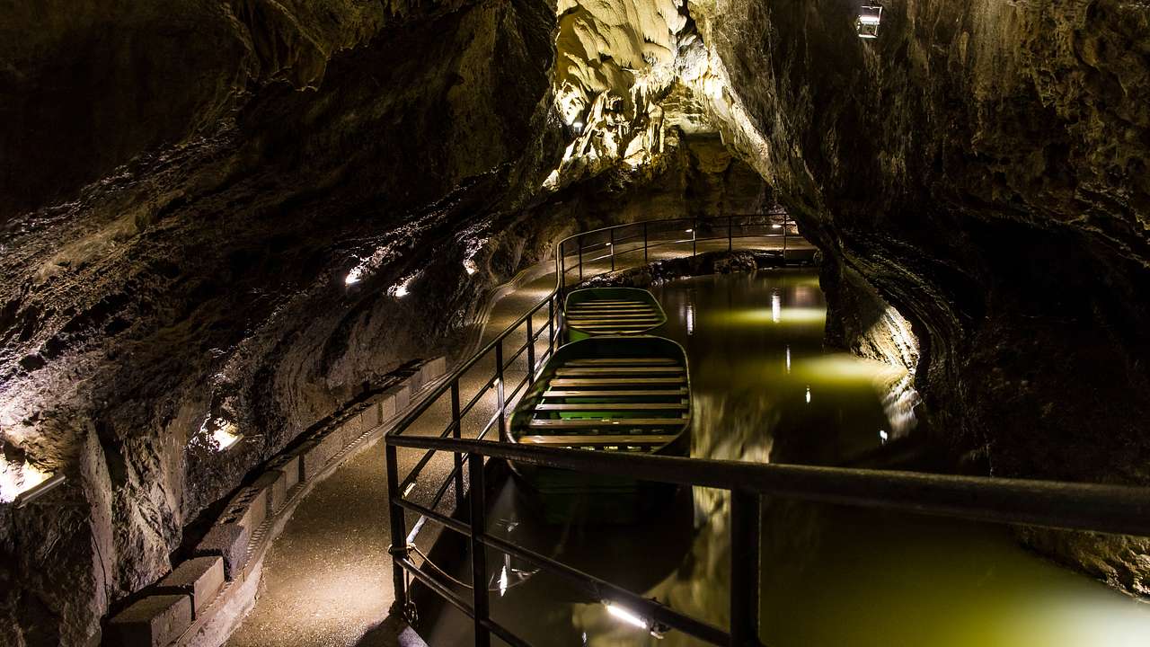 A pathway inside a cave beside a body of water and a boat