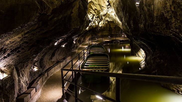 A pathway inside a cave beside a body of water and a boat