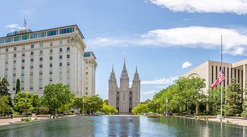 A pool of water with a tall building, US flag, and castle-like building in front