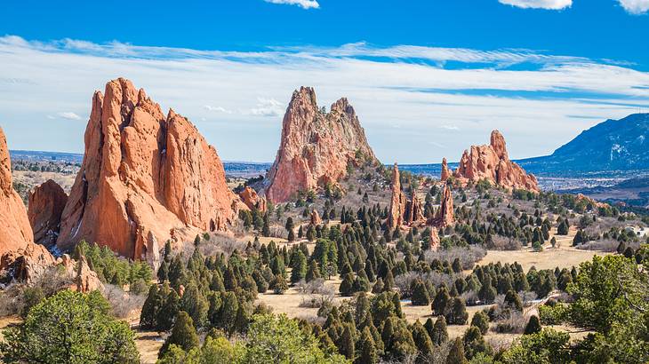 Red rock mountains with small green trees surrounding them