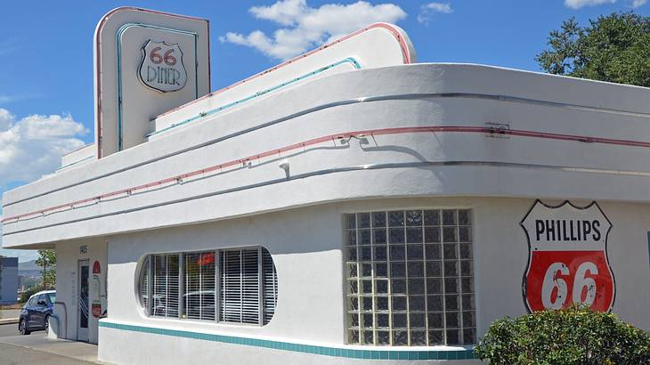 A unique white building with a retro "Diner 66" sign under a blue sky with clouds