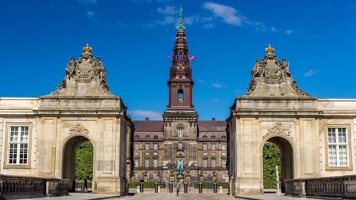 A large building with a tall tower and two large concrete archways in front