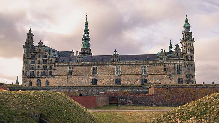 A Renaissance Era stone castle with a tower in the middle under a cloudy sky