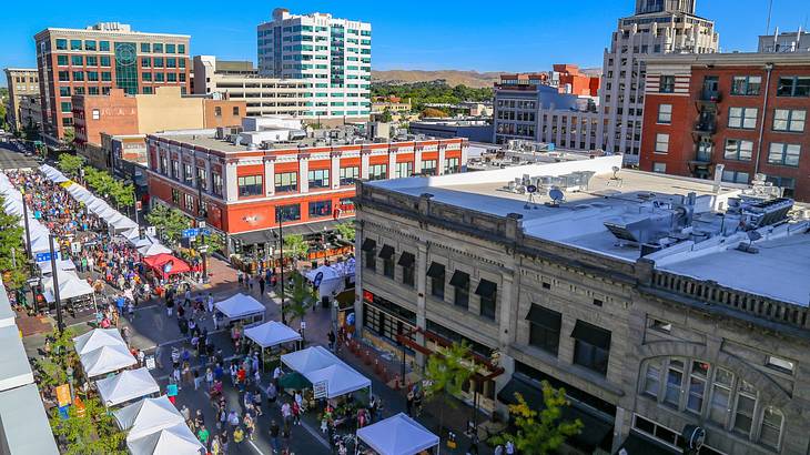 An aerial view of a street market surrounded by city buildings under a blue sky