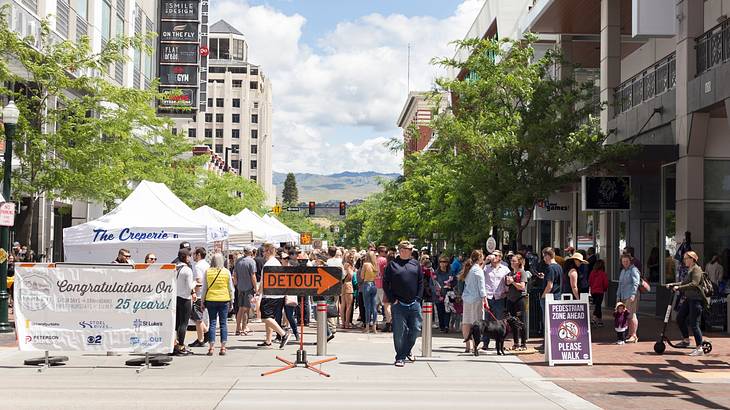 A market on a city street with lots of people next to buildings