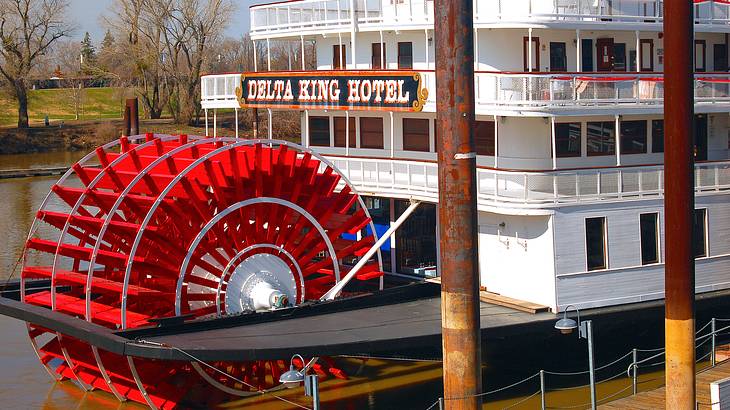 A white boat with a "Delta King Hotel" sign and a wheel-shaped red paddle behind it