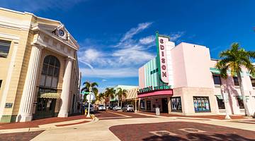 A street with retro buildings and palm trees under a blue sky