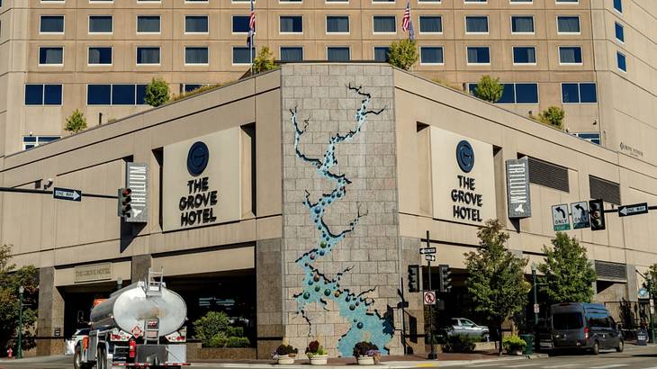 A hotel with a sign that says "The Grove Hotel" next to a road with cars and trucks