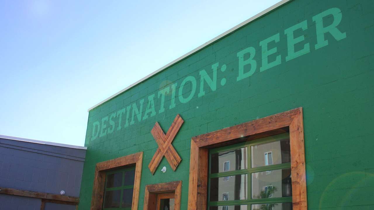 An industrial style building painted green with a sign that says "Destination: Beer"