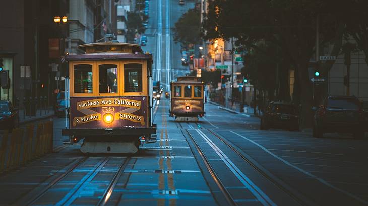 Two cable cars on a road at night