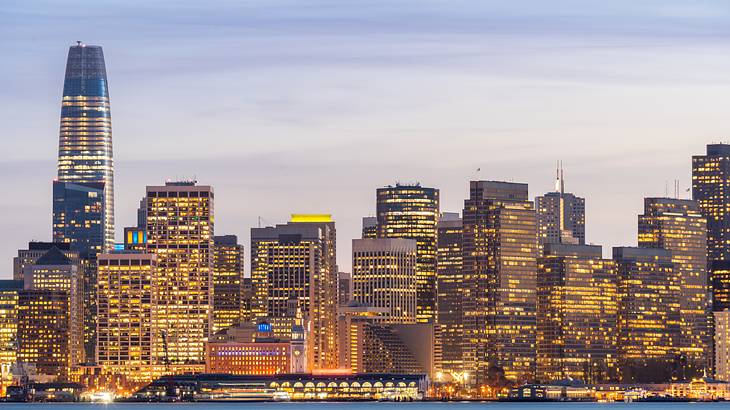 A skyline at night with water in front of it