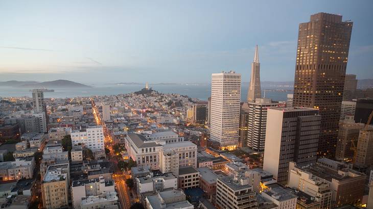 Aerial view of a city at night with a bay in the distance