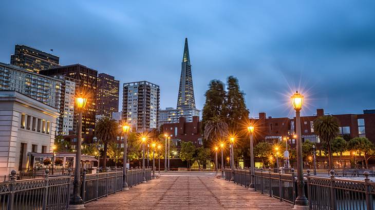 A pier at dusk with skyscrapers in front of it