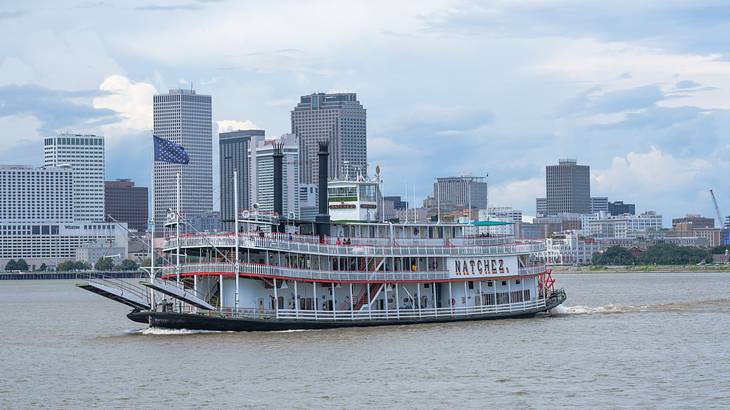An old-fashioned Steamboat Natchez on the water with a city skyline behind