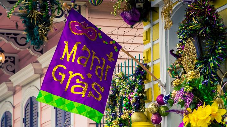A purple flag that says Mardi Gras on a house decorated with Mardi Gras decorations