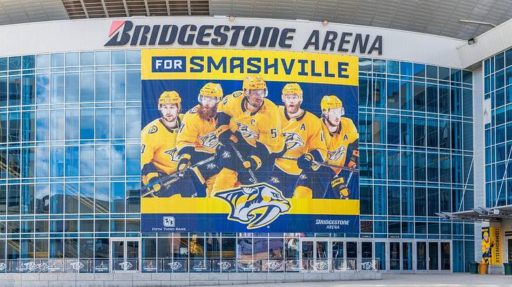 An arena with a glass front that says "Bridgestone Arena" and a hockey banner on it An arena with a glass front that says "Bridgestone Arena" and a hockey banner on it