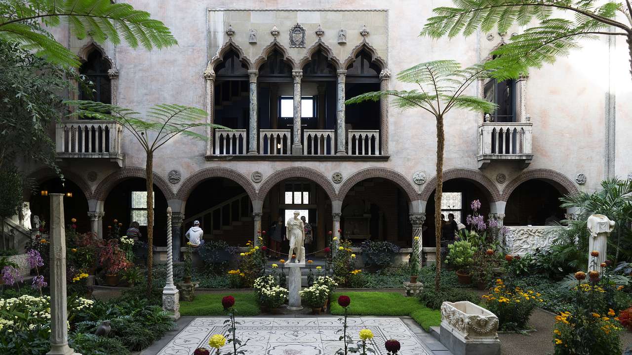 A garden courtyard with greenery, a statue, and a building wall behind it