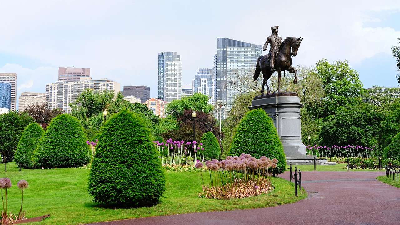 A statue of a man on a horse with a path and green garden surrounding it