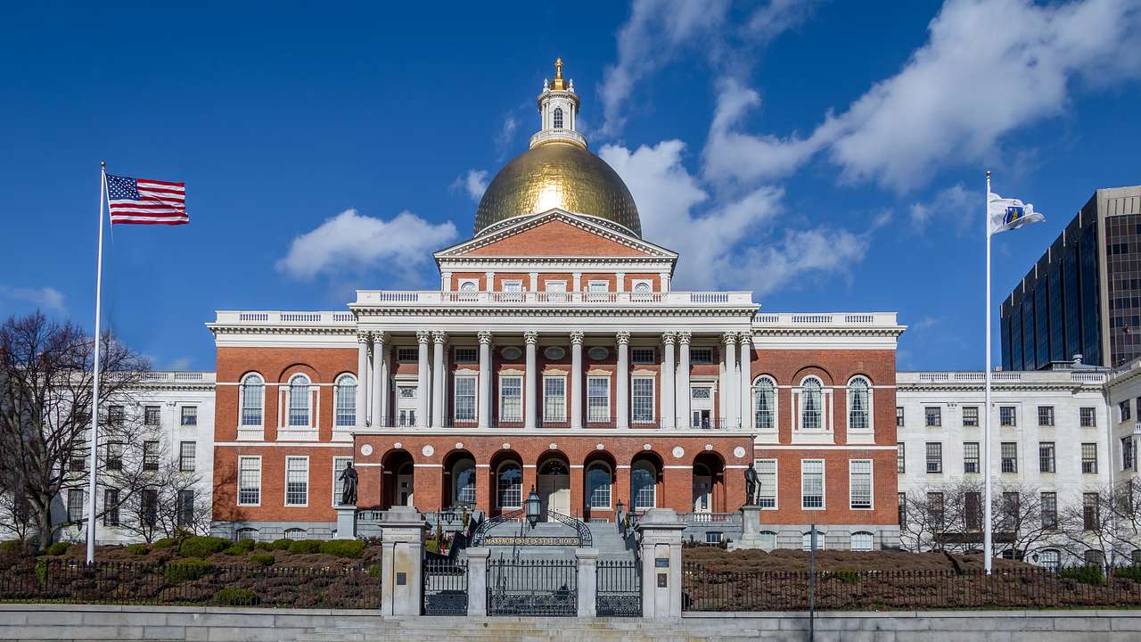 A red brick and white building with a gold dome roof and a US flag out the front
