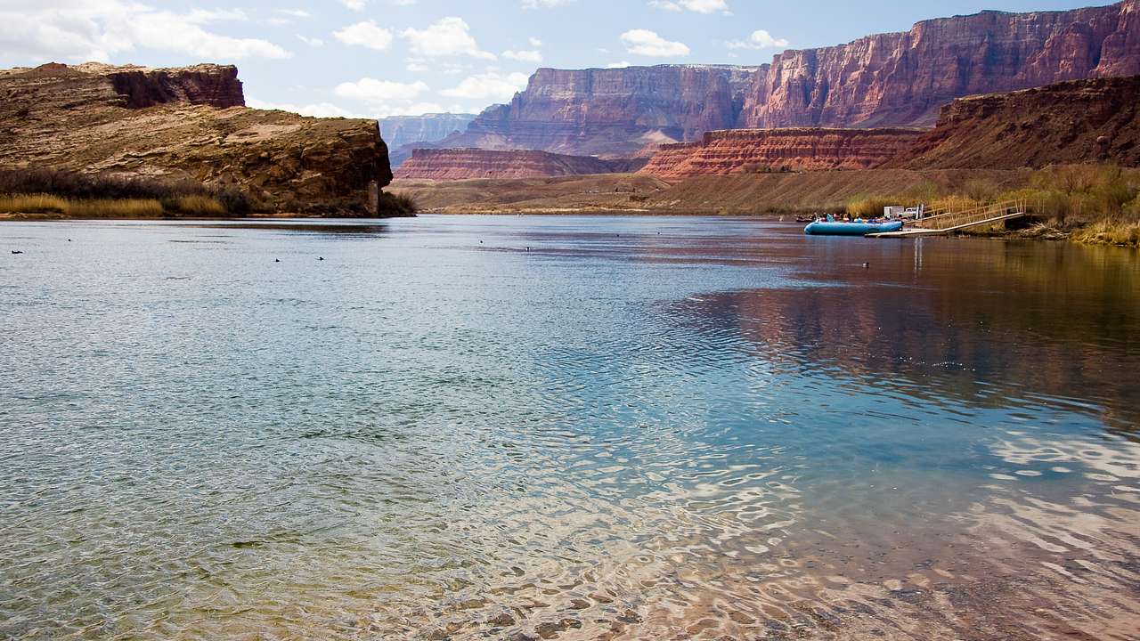 A body of water with a boat on it and red rock mountains surrounding it