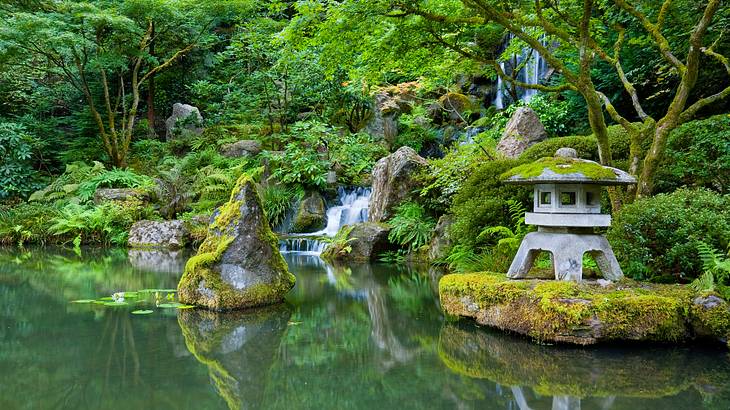A small concrete Japanese teahouse surrounded by greenery along with a pond A small concrete Japanese teahouse surrounded by greenery along with a pond