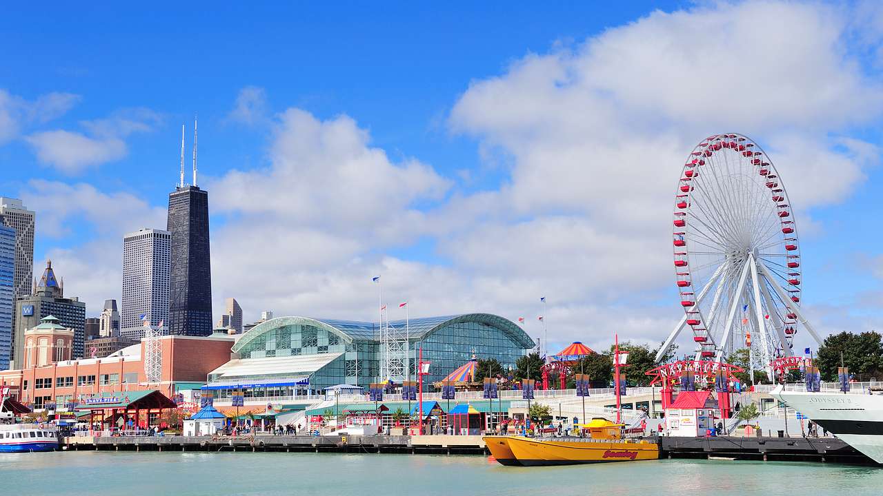 A waterfront area with colorful buildings, a Ferris wheel, and skyscrapers behind