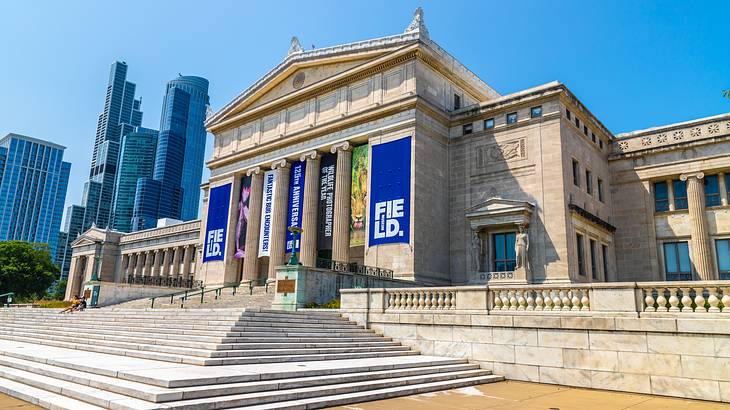 A stone museum building with steps leading up to it, and a skyline behind