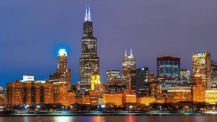 The Chicago skyline at night with water in front of it