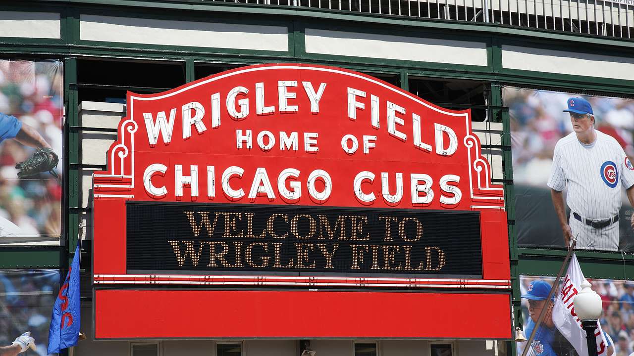 A red sign that says "Wrigley Field" "Home of the Chicago Cubs"