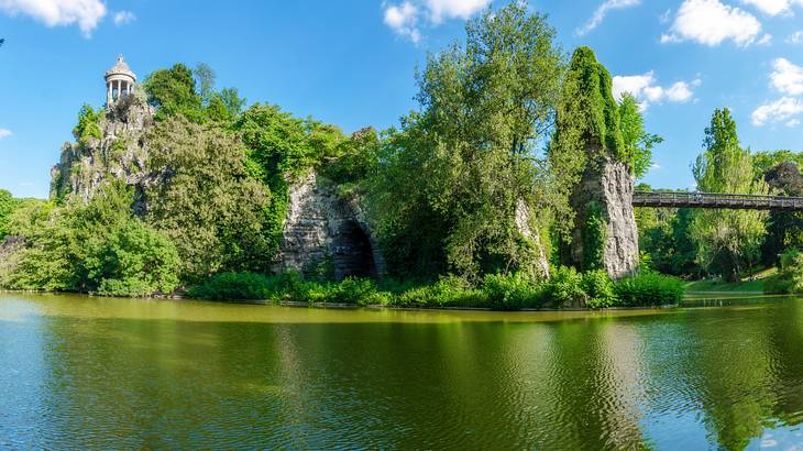 Panoramic view of Buttes-Chaumont Park with greenery and water in front on a nice day