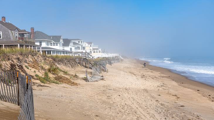 A sandy beach next to beach houses and the ocean