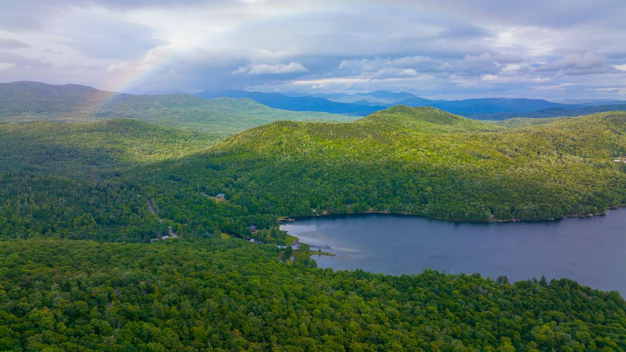 A lake surrounded by highly dense forest with a rainbow over it