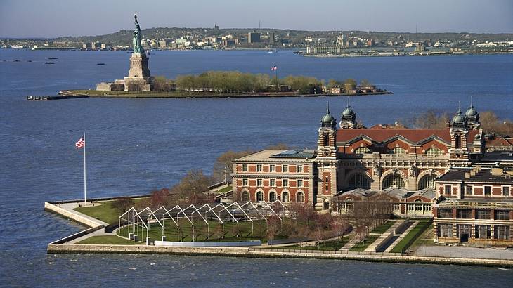 An old-fashioned building on an island with the Statue of Liberty behind it