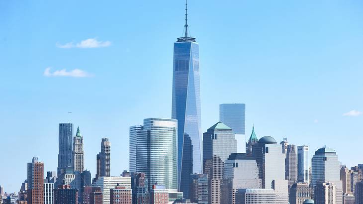 A very tall skyscraper surrounded by smaller skyscrapers under a blue sky