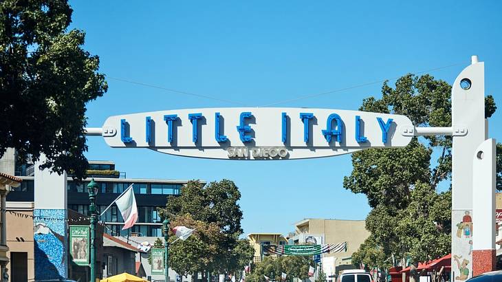 A sign over a street that says "Little Italy, San Diego" next to trees and buildings A sign over a street that says "Little Italy, San Diego" next to trees and buildings