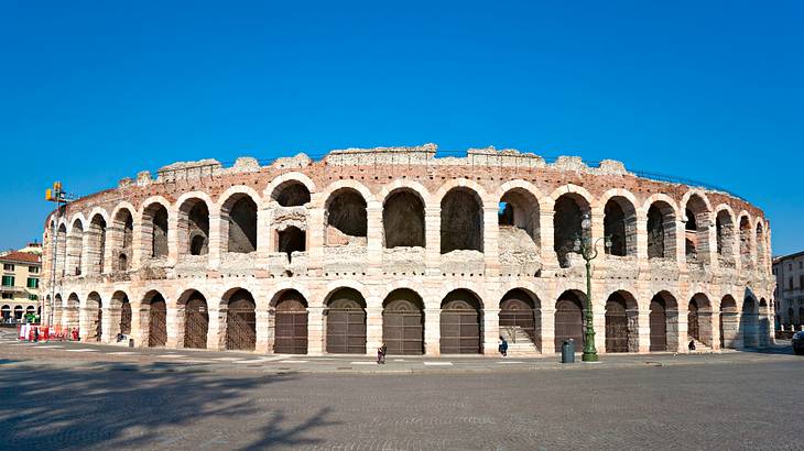 The outside architecture of a Roman amphitheatre against a clear blue sky