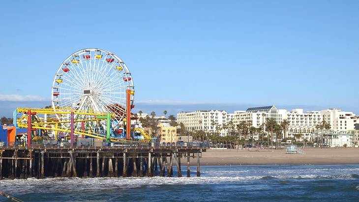 A beach with a colorful Ferris wheel on the left-hand side under a blue sky