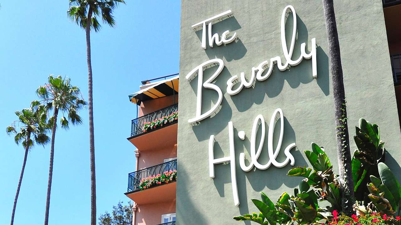 A hotel with a green wall and a sign that says "The Beverly Hills"