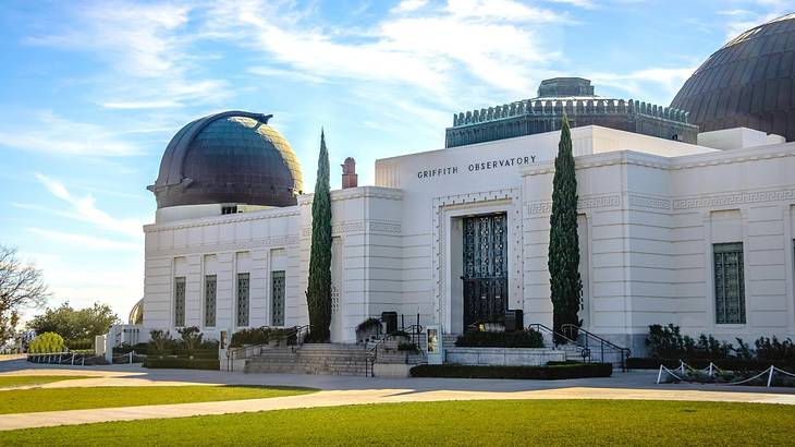 A white building with black domed roofs and grass in front of it