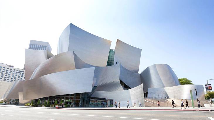 A modern silver building with a street in front of it under a clear sky