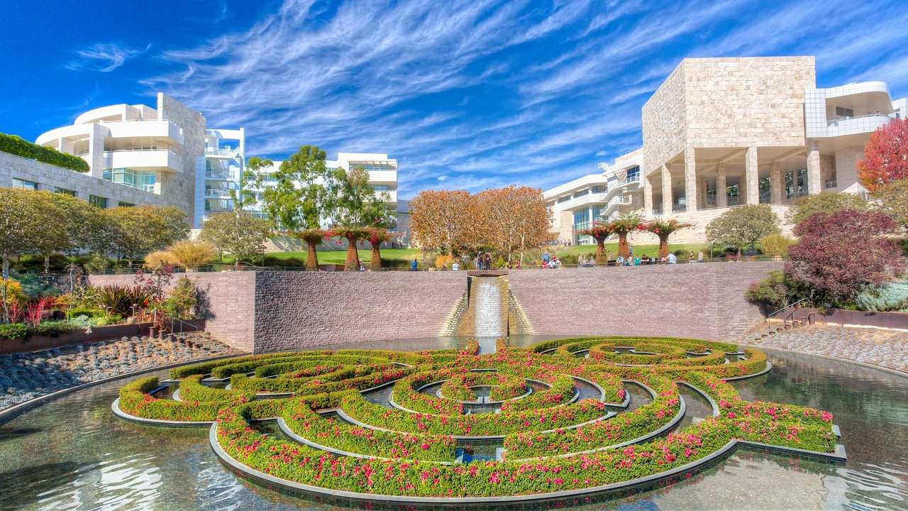 A garden and water feature with white buildings behind it