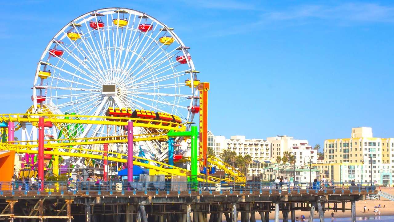 A colorful Ferris wheel and roller coaster on a pier